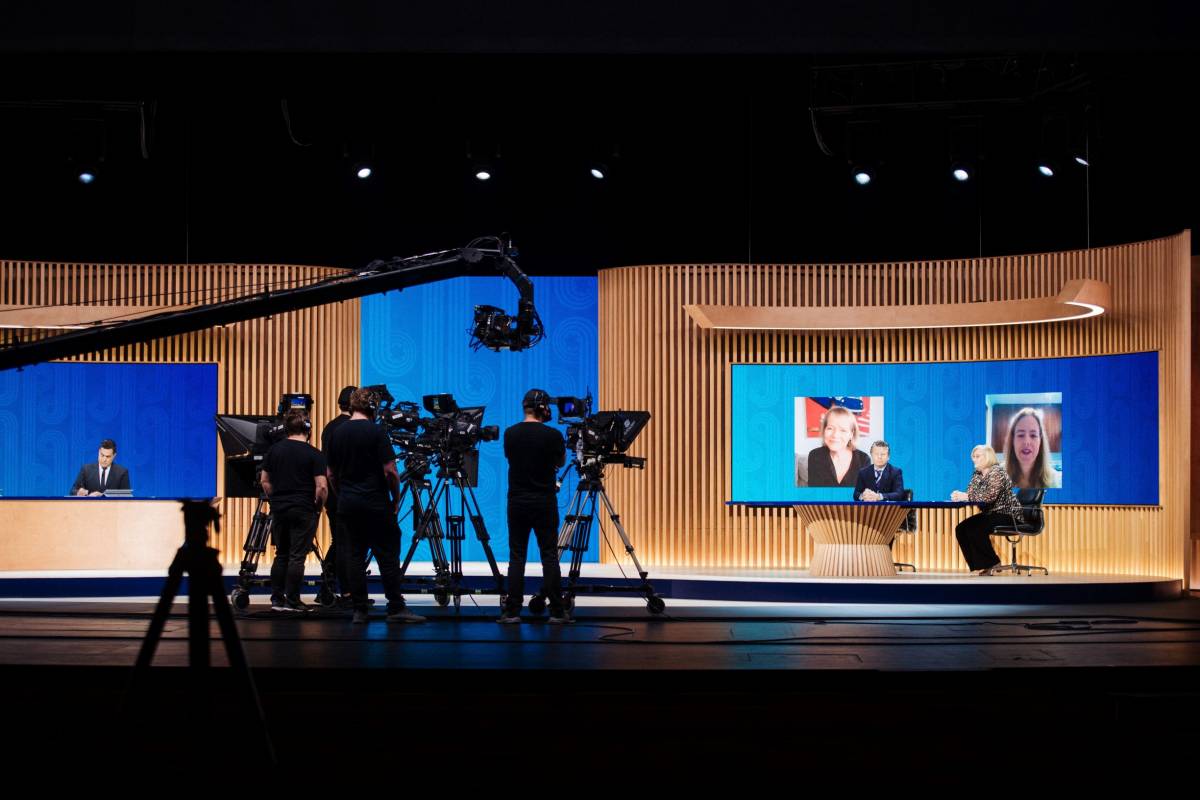 Wide shot of the APEC CEO Summit 2021 set including stage, desk and camera crew.. 